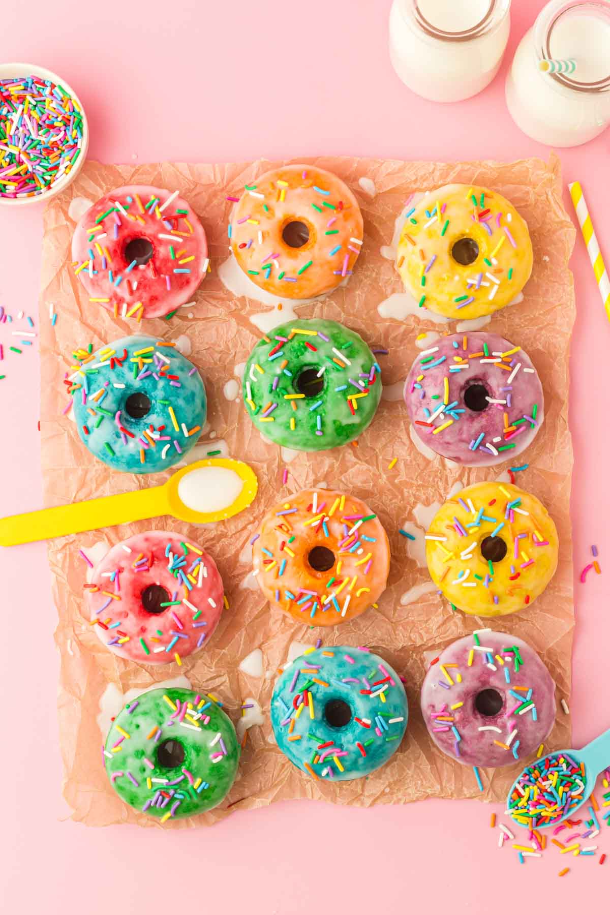 frosted rainbow donuts on a piece of parchment