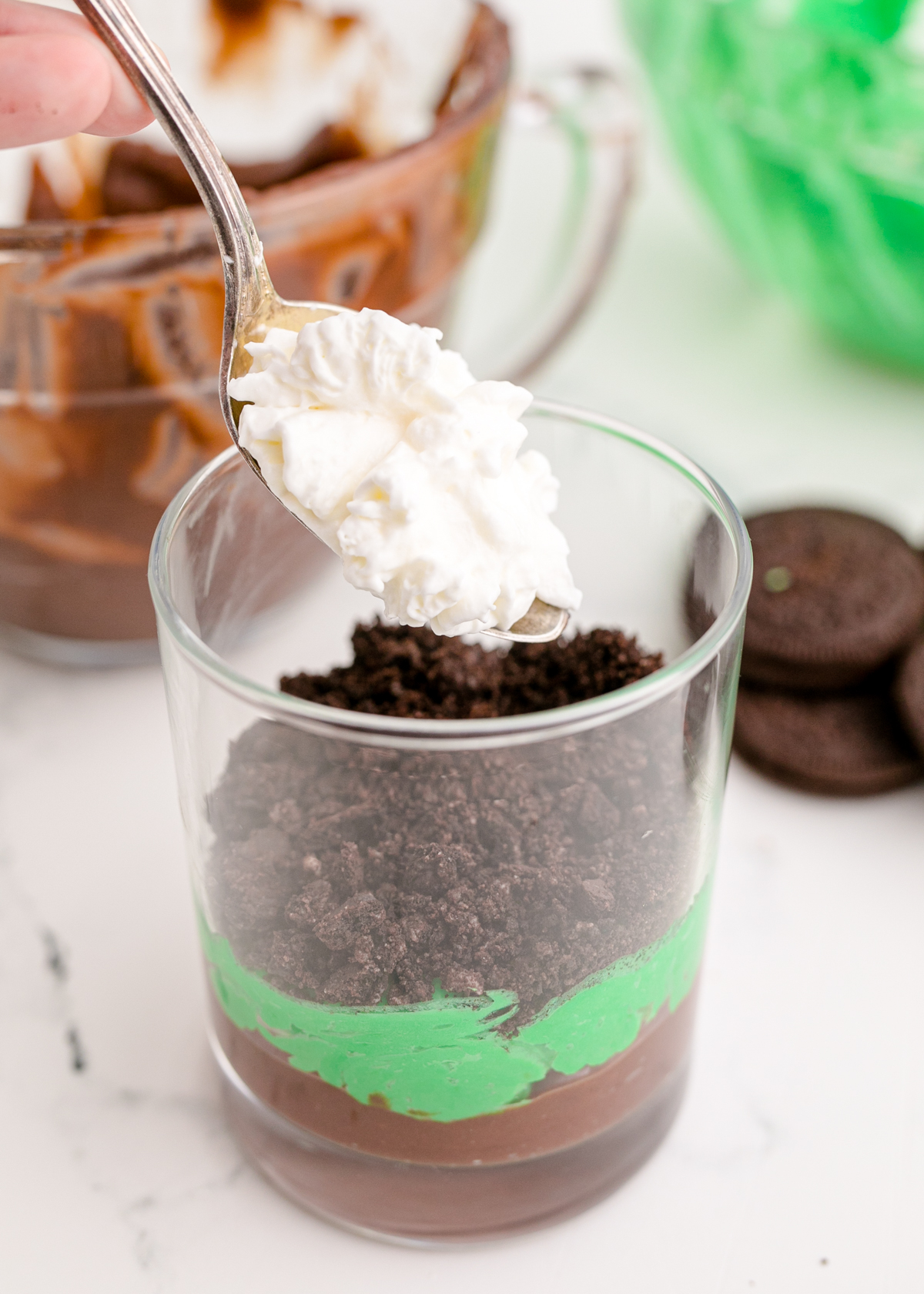 adding whipped cream to a St. Patrick's Day pudding cup