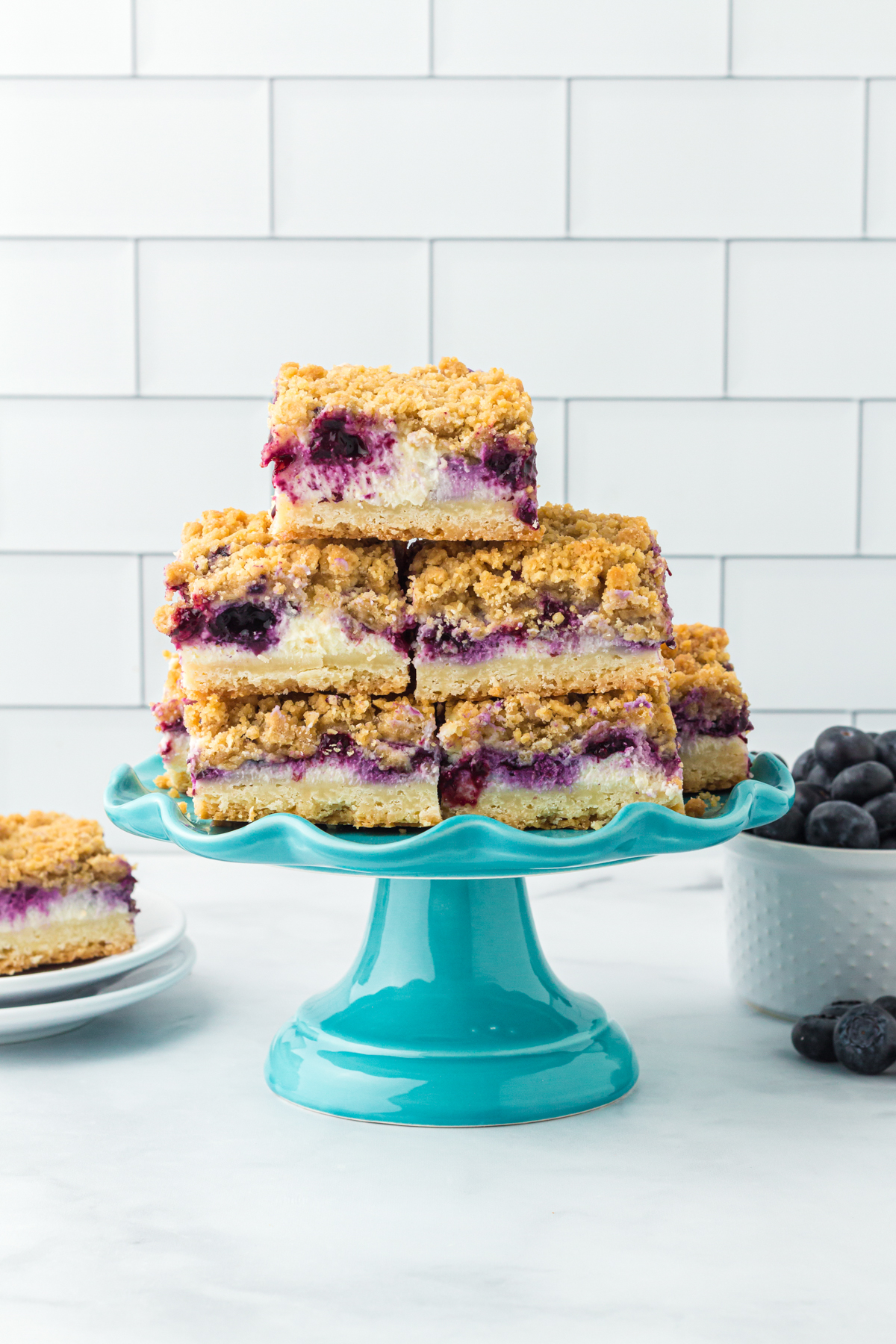 cake stand with a stack of blueberry cheesecake bars