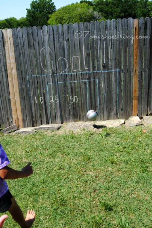 kid kicking soccer ball at fence