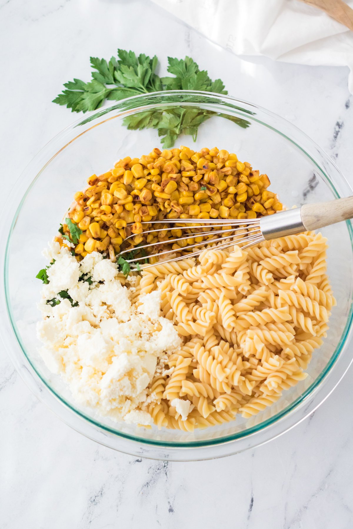 glass bowl with pasta, corn, and cheese
