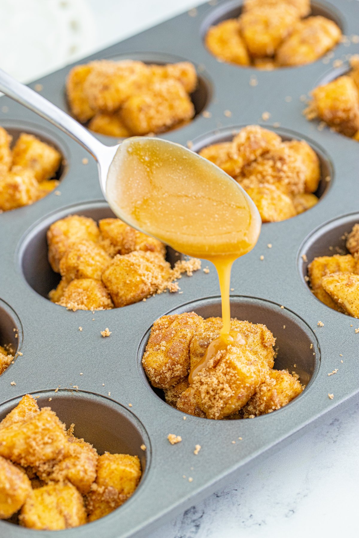 pouring butter mixture over monkey bread muffins
