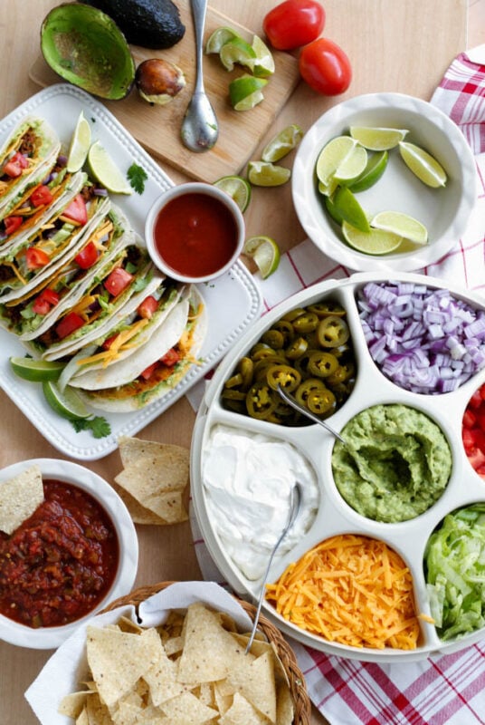 Taco bar with a chip and dip container full of toppings