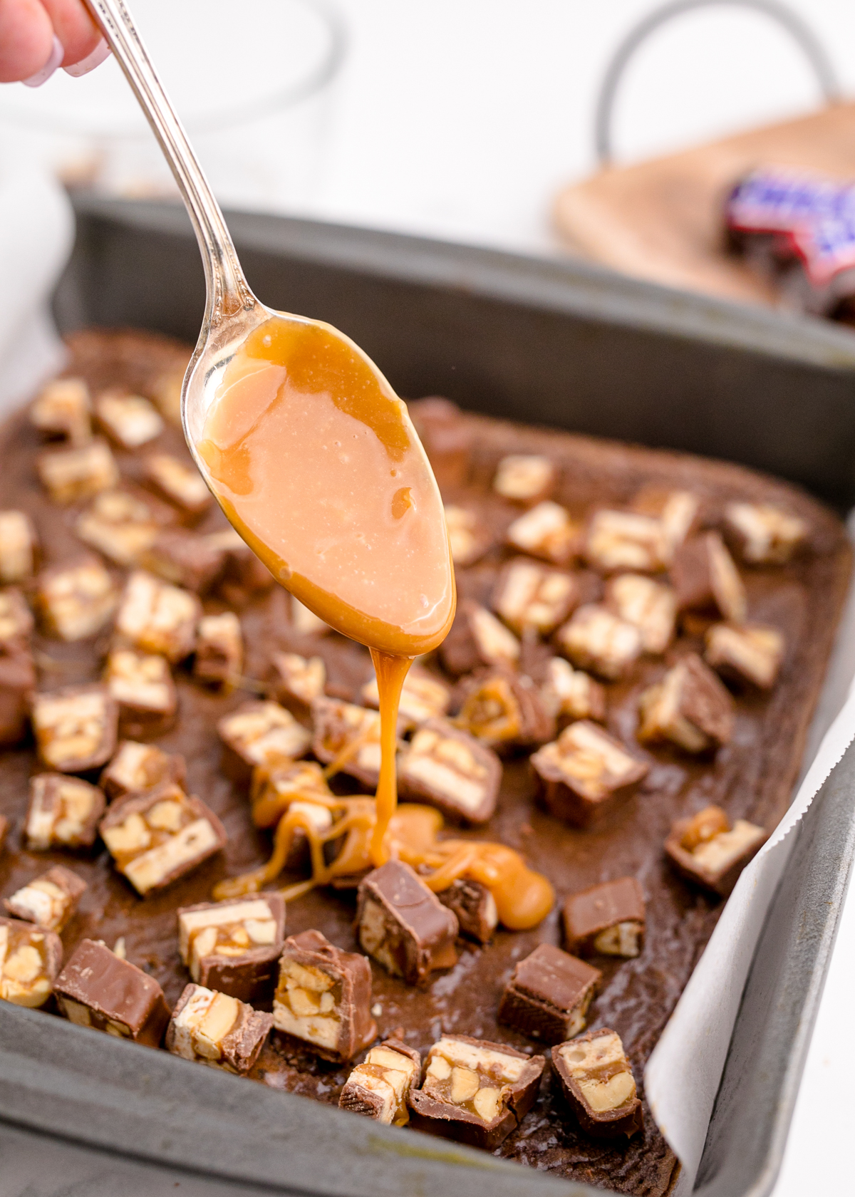 drizzling melted caramel over Snickers brownies