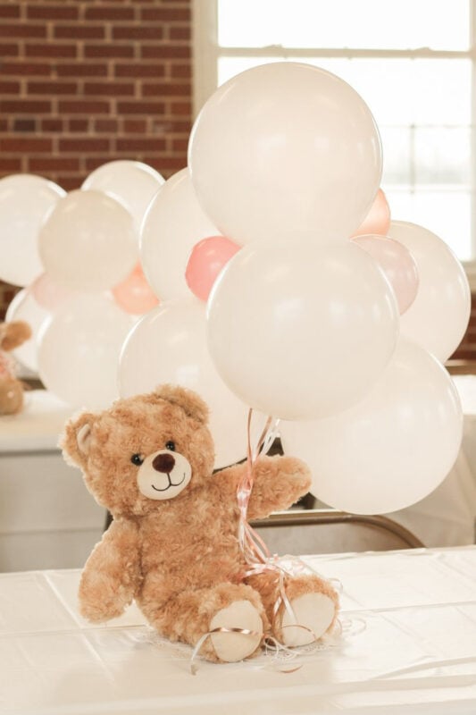 teddy bear holding white balloons