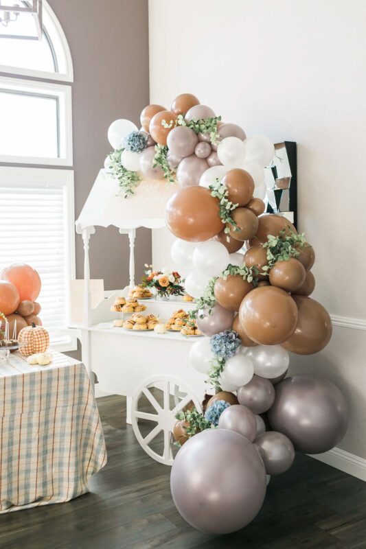 food cart with pumpkin treats and a balloon arch