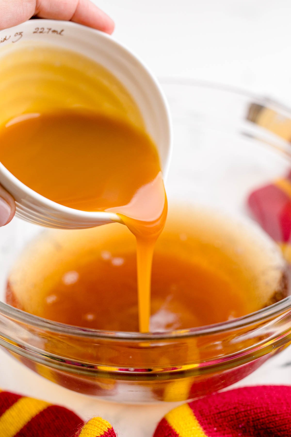 pouring butterscotch topping into a glass bowl