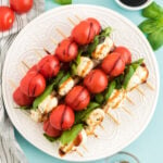 round white plate with caprese salad skewers stacked on it