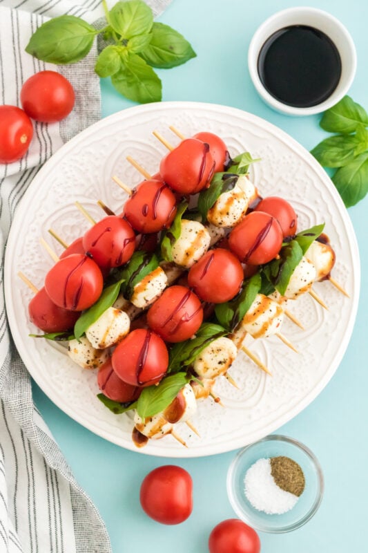 round white plate with caprese salad skewers stacked on it