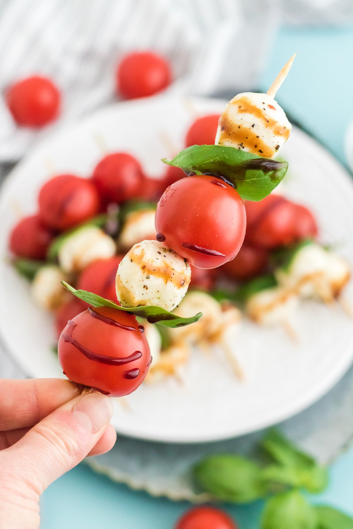 hand holding a glazed caprese salad skewer