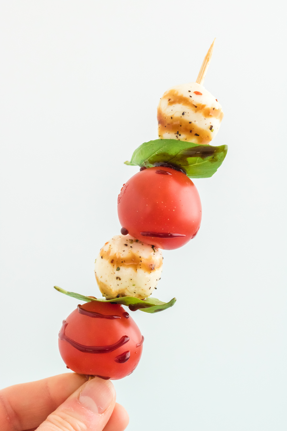 hand holding a caprese skewer