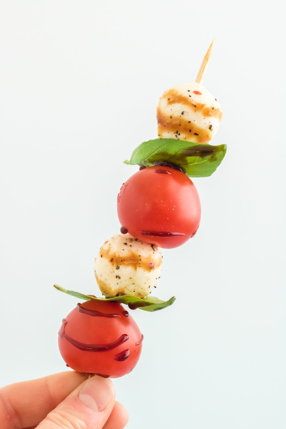 hand holding a caprese skewer