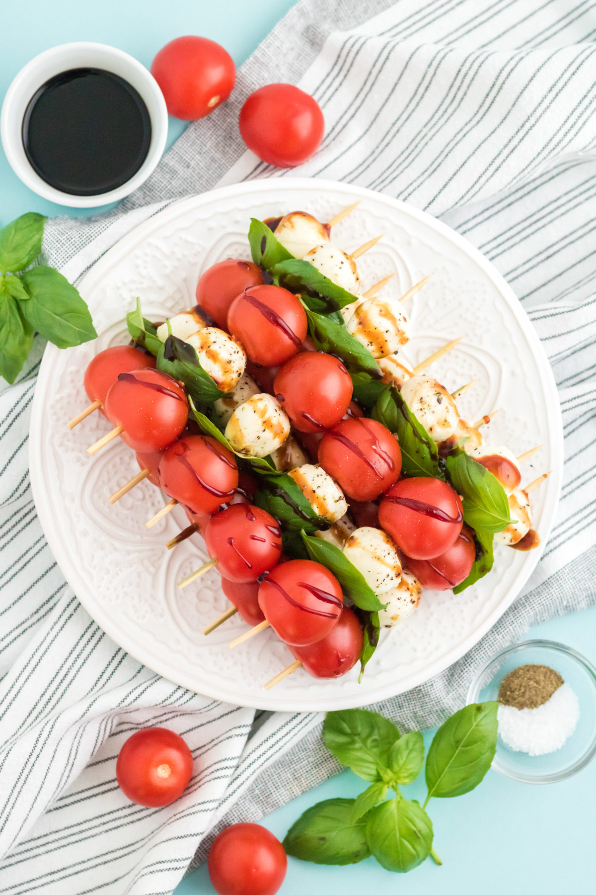 white plate filled with caprese salad skewers