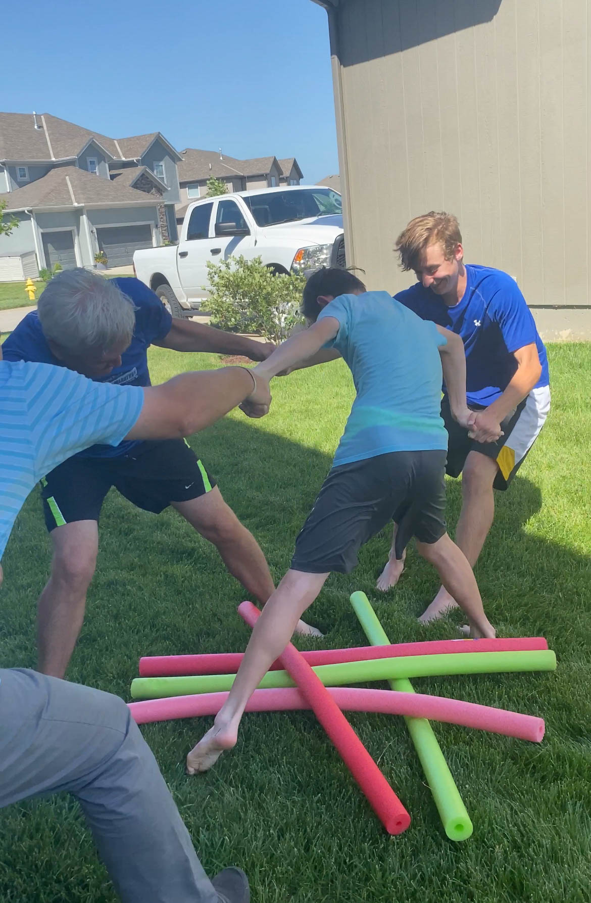 a bunch of people jumping over pool noodles