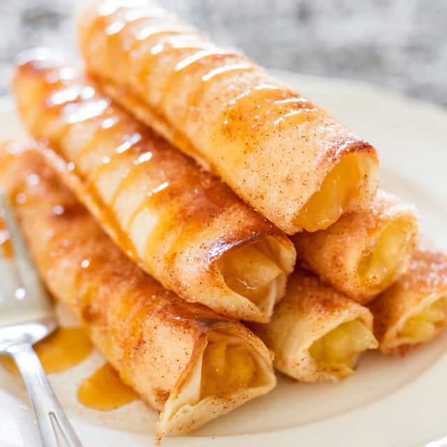 stack of apple pie taquitos on a white plate
