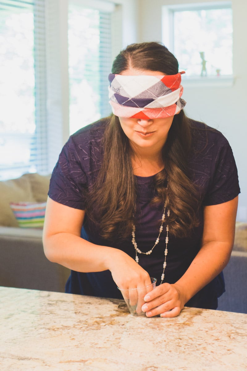woman blindfolded with her hand in a plastic cup