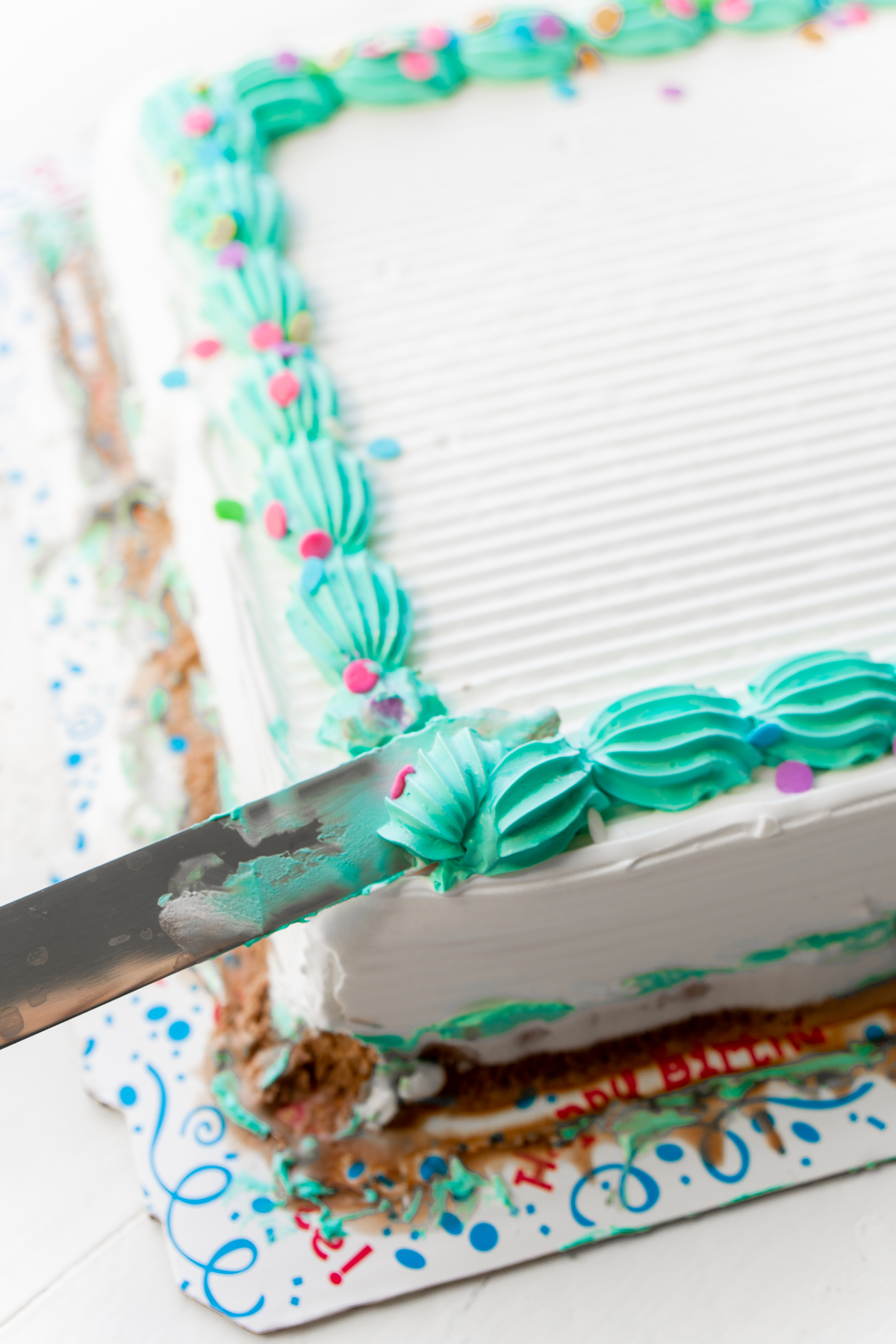 knife removing blue frosting from an ice cream cake