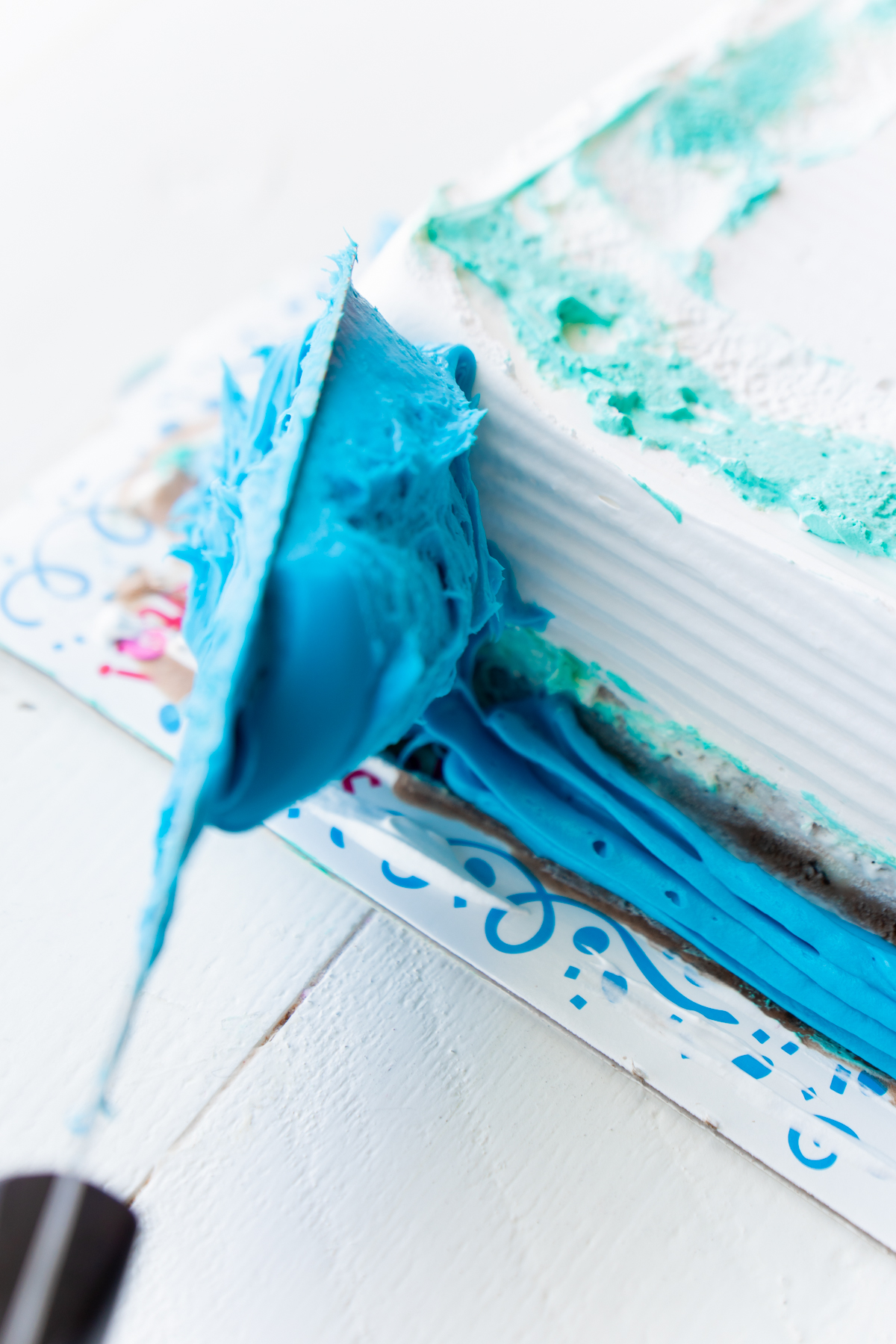 adding blue frosting to an ice cream cake