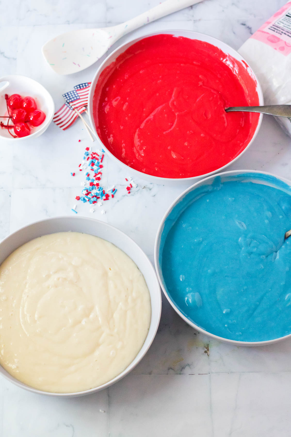 three cake pans with colored cake batter