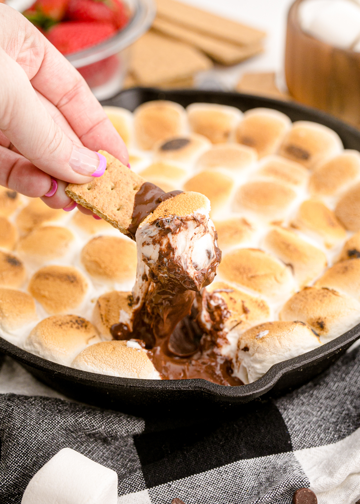 hand dipping graham crackers into a smores dip