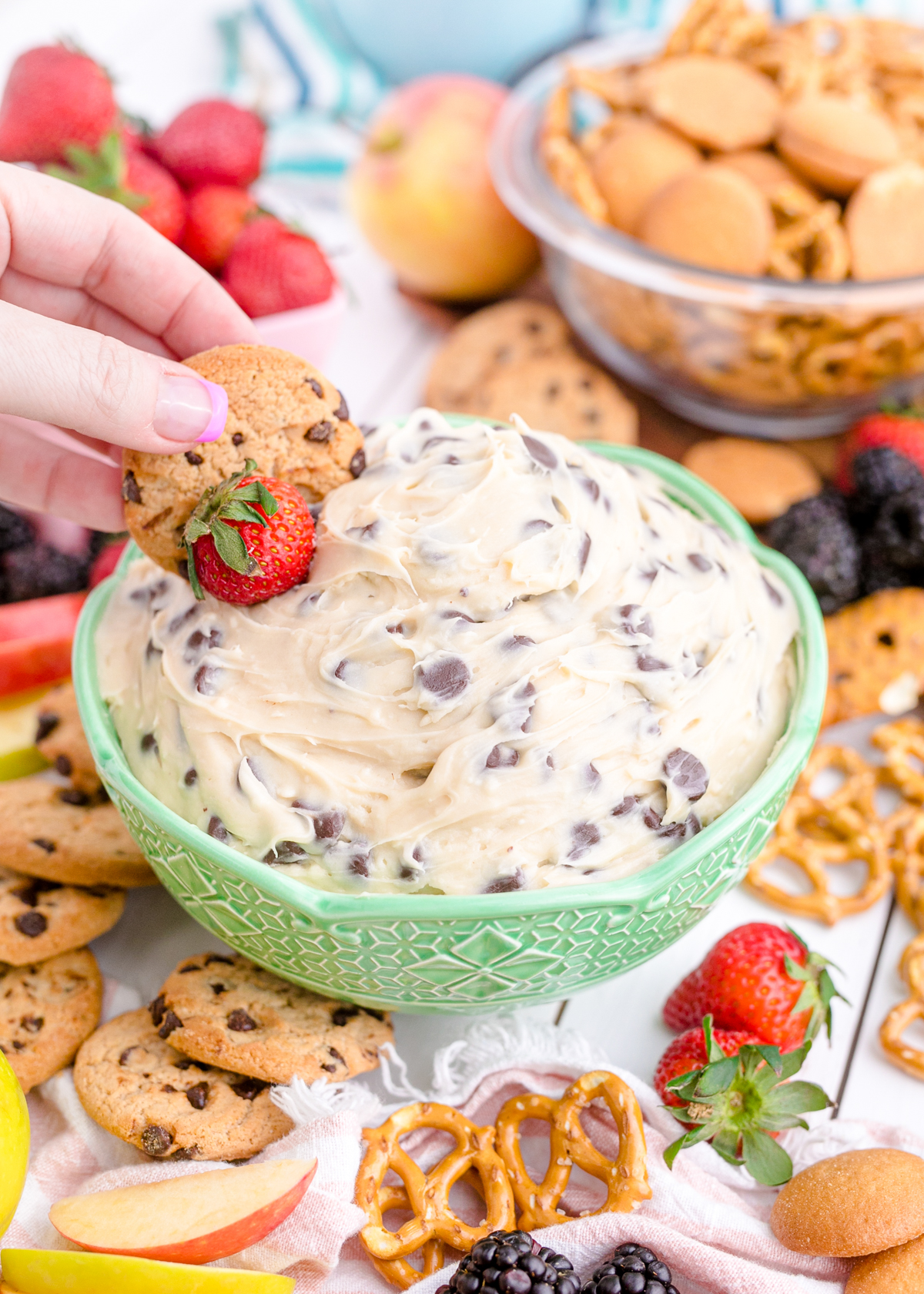 hand dipping a cookie in chocolate chip cookie dough dip