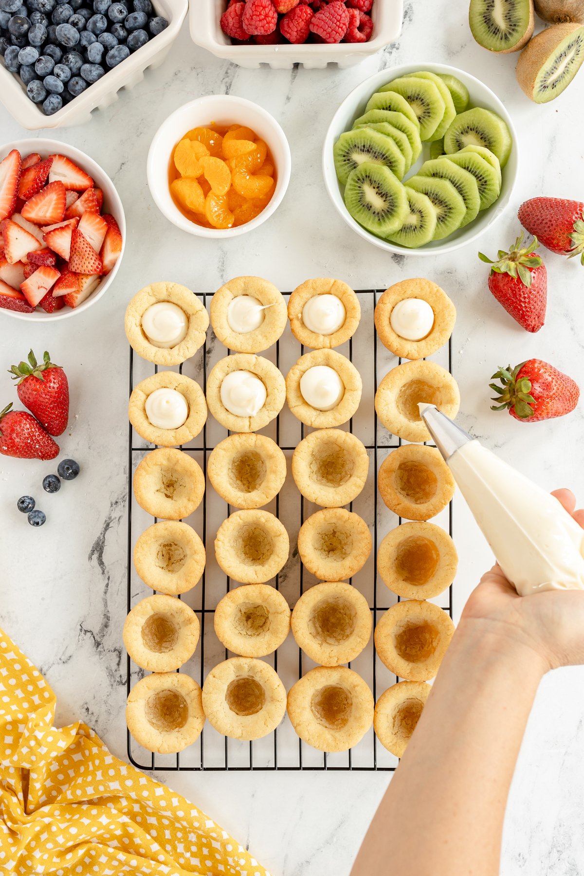 pipe bag filling fruit tarts with cream cheese