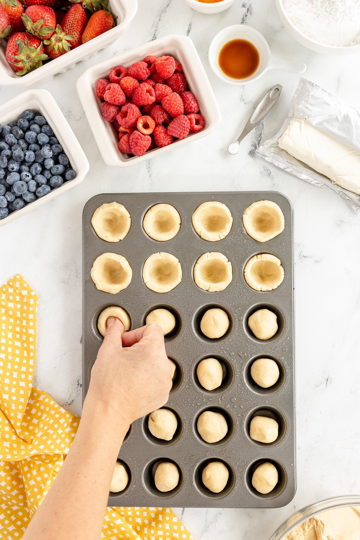 hand pressing in crust for mini fruit tarts