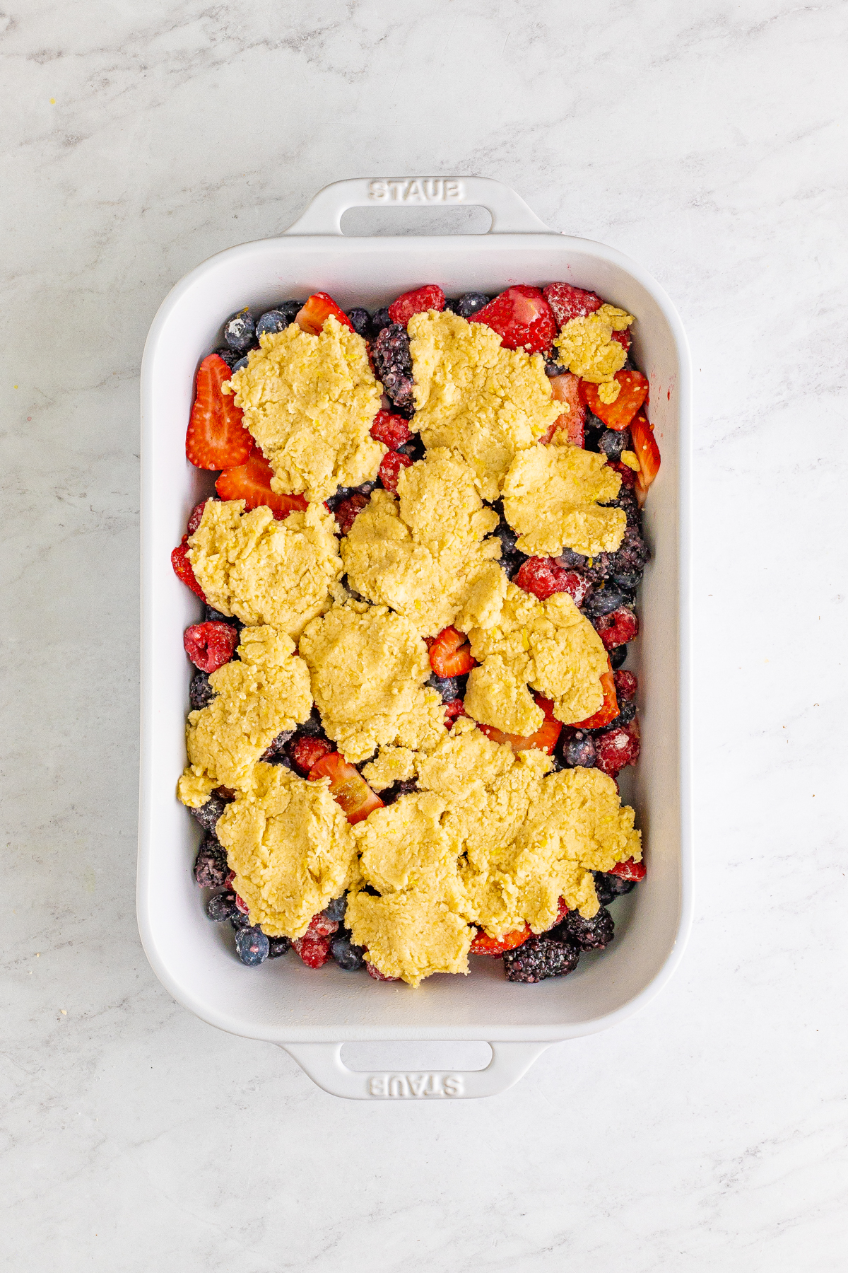 baking dish with unbaked mixed berry cobbler