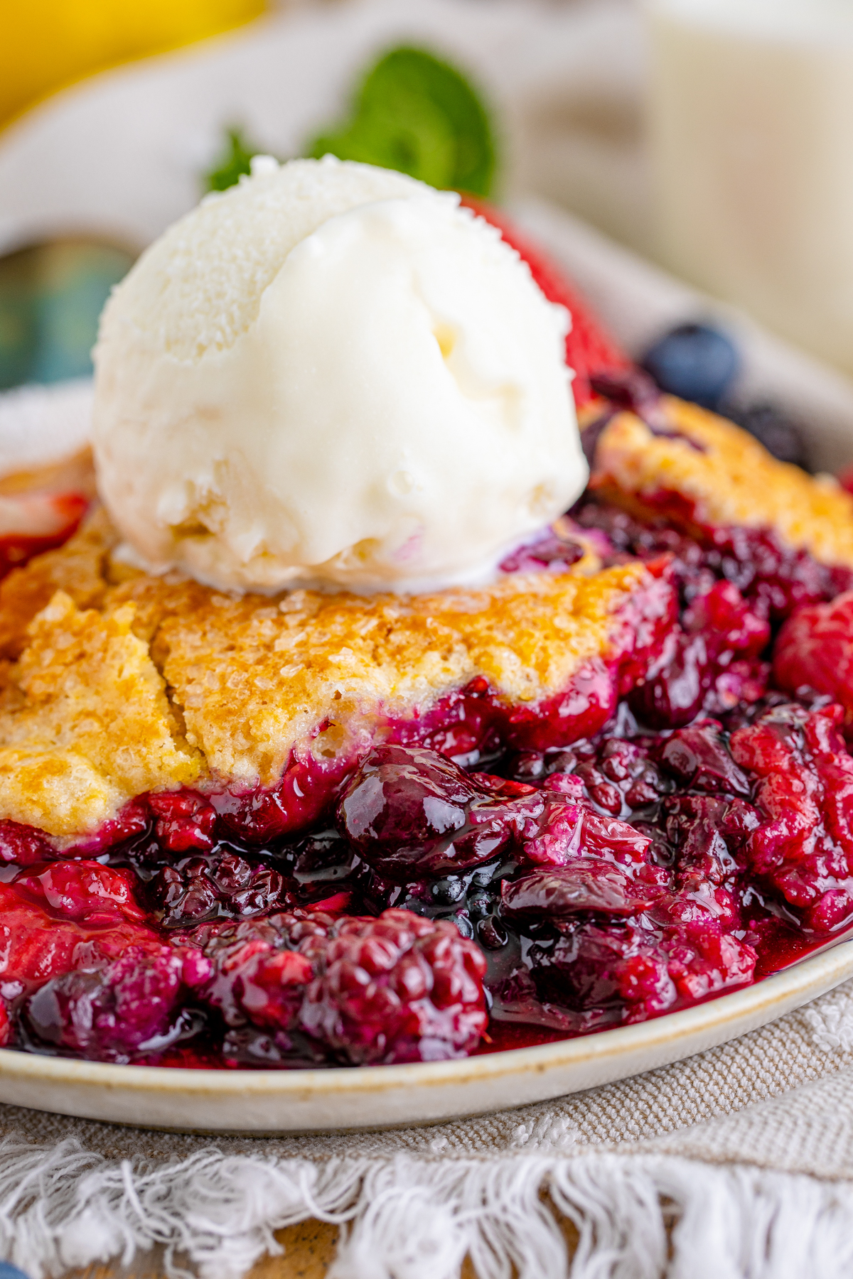 Piece of mixed berry cobbler with ice cream on top