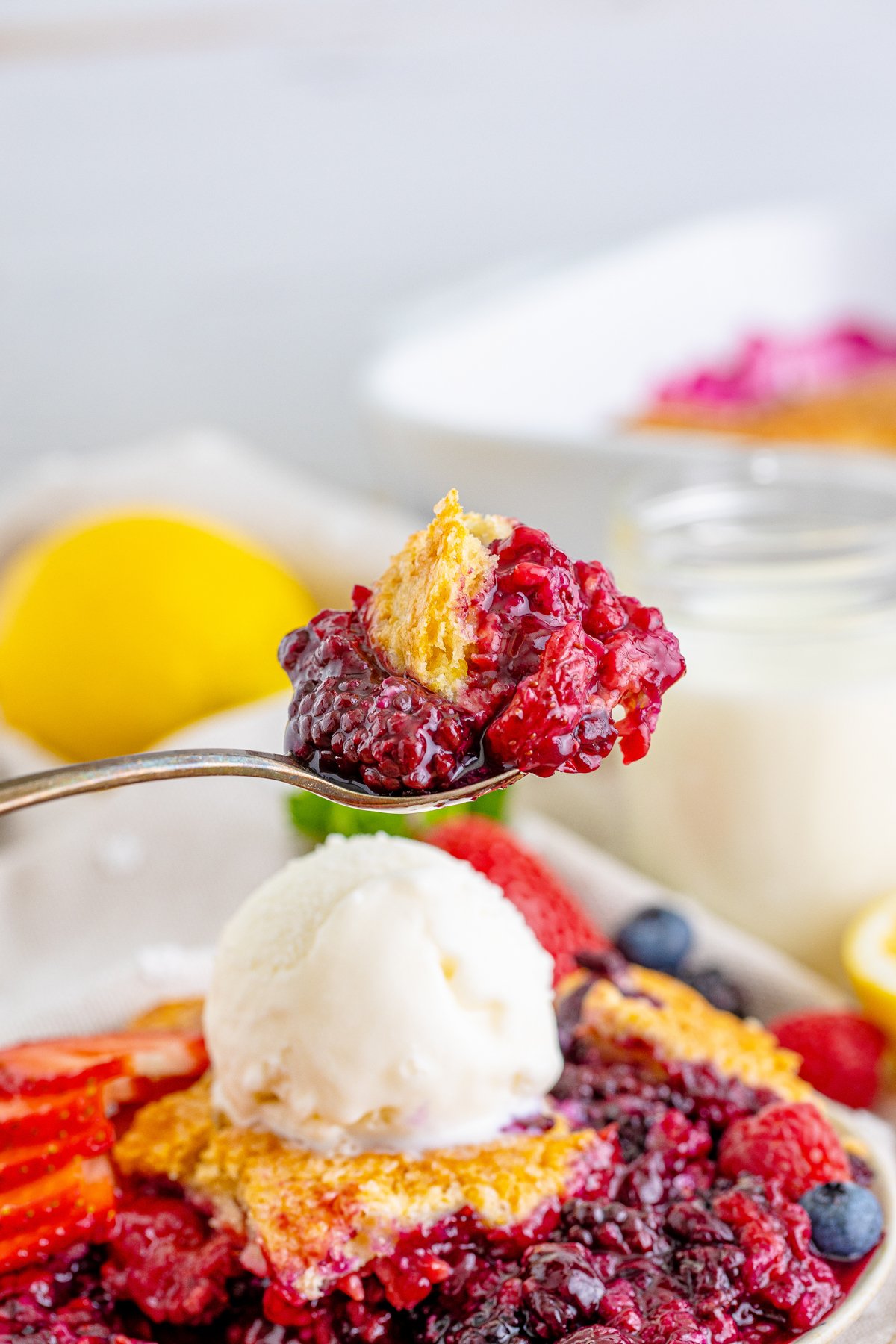 spoon full of mixed berry cobbler above a piece