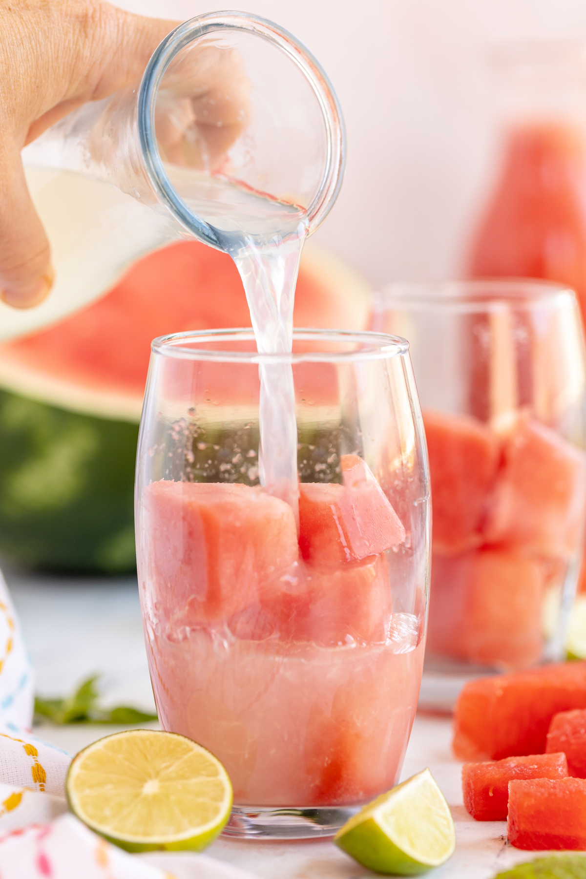 pouring lemonade into a glass with watermelon cubes