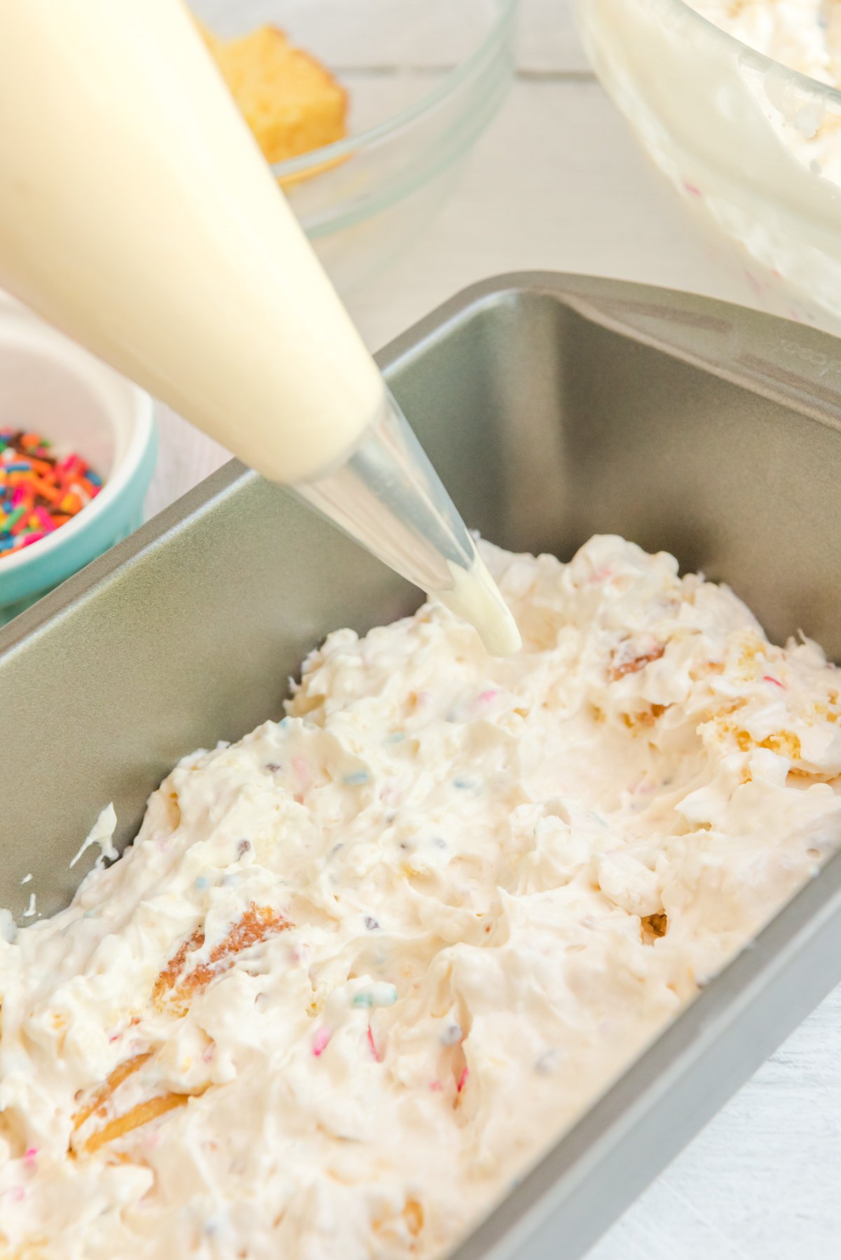 piping bag adding frosting to a loaf pan