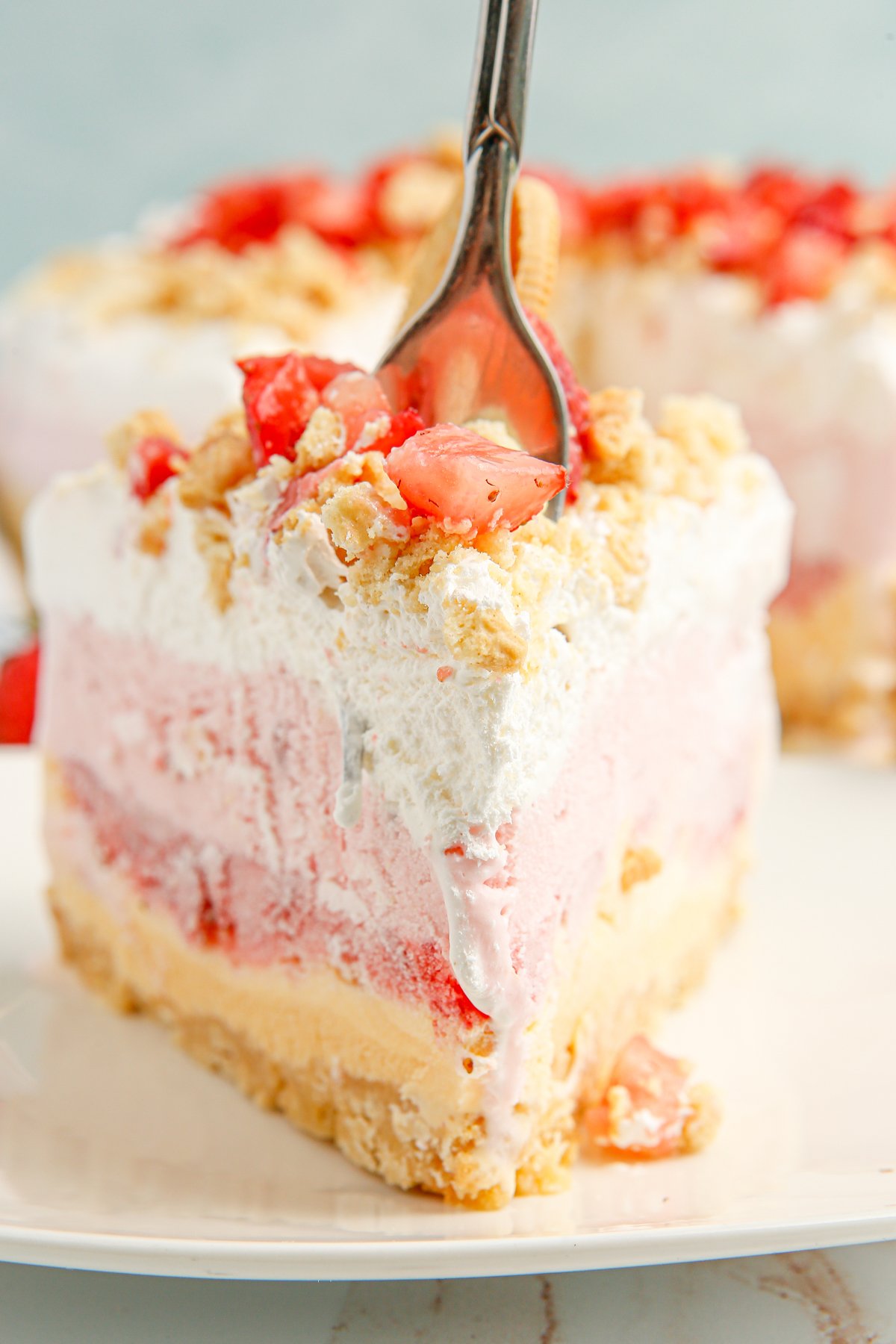 fork taking a bite of strawberry ice cream cake