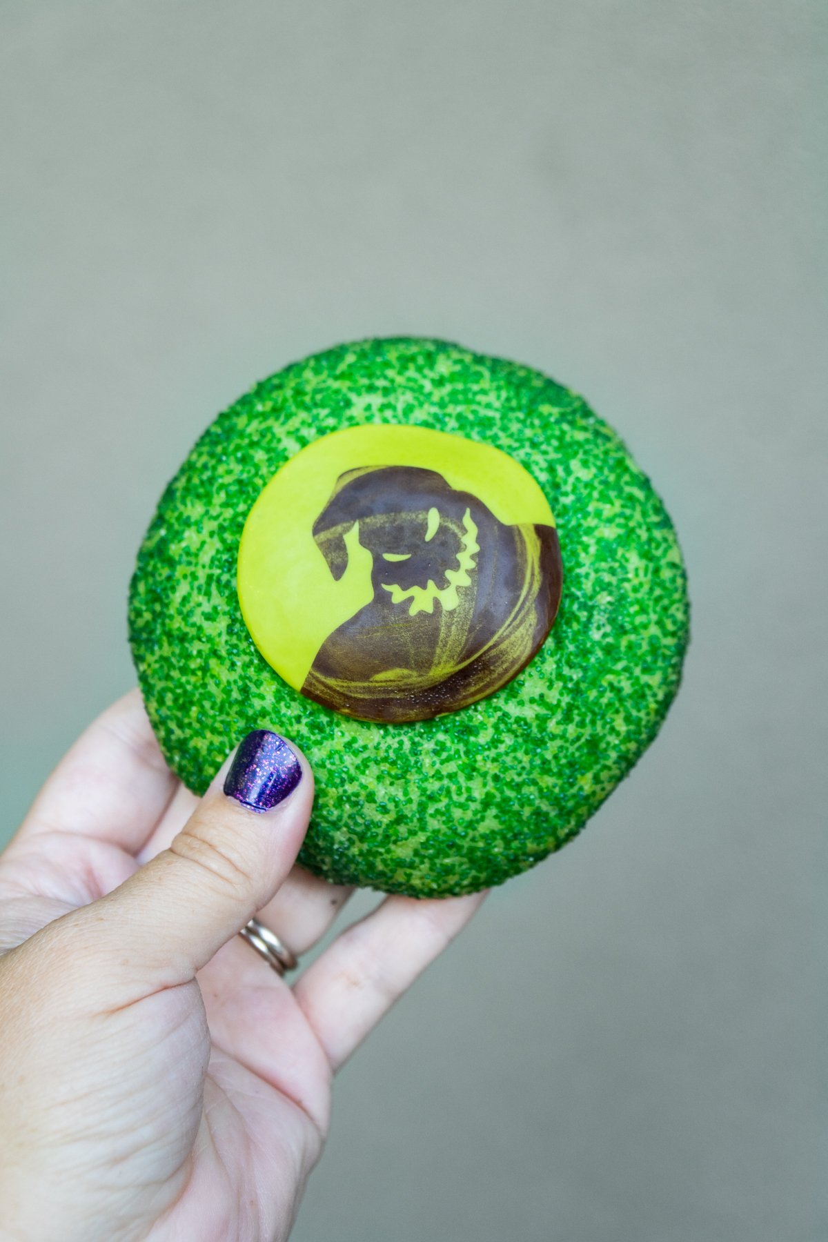 hand holding a green cookie with Oogie Boogie on it