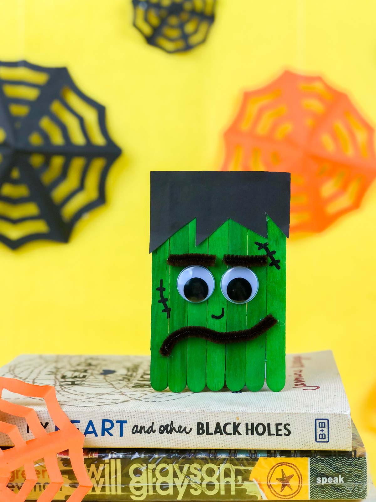Frankenstein craft made out of popsicle sticks on a stack of books