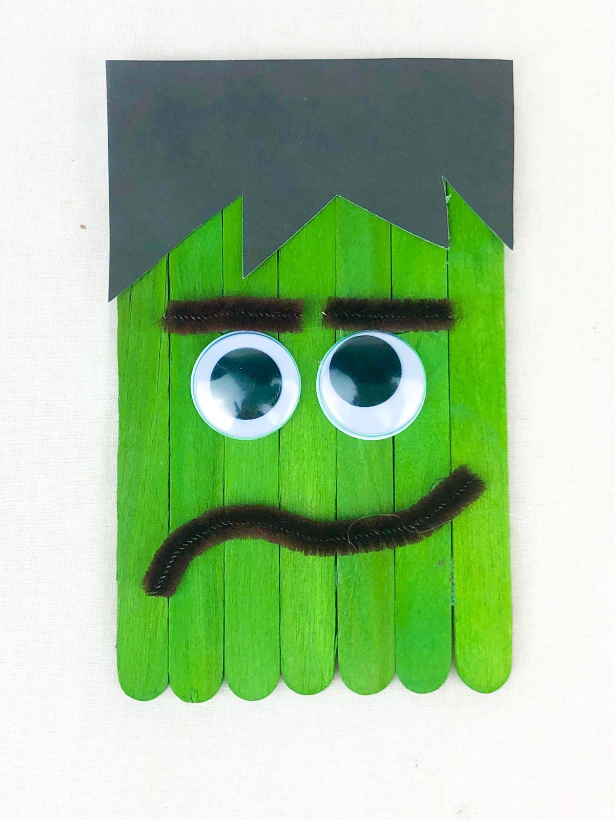 Green popsicle sticks with a Frankenstein face