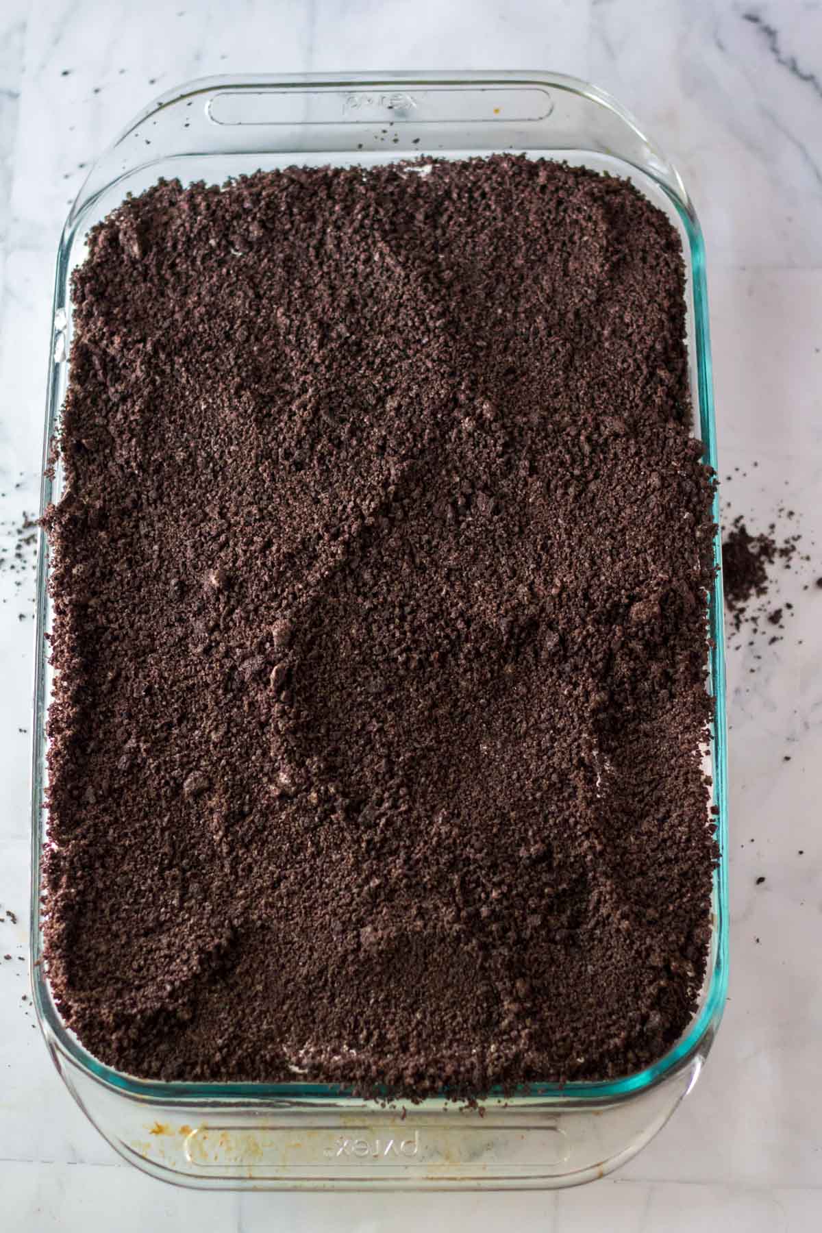 Oreo crumbs on top of a pudding poke cake