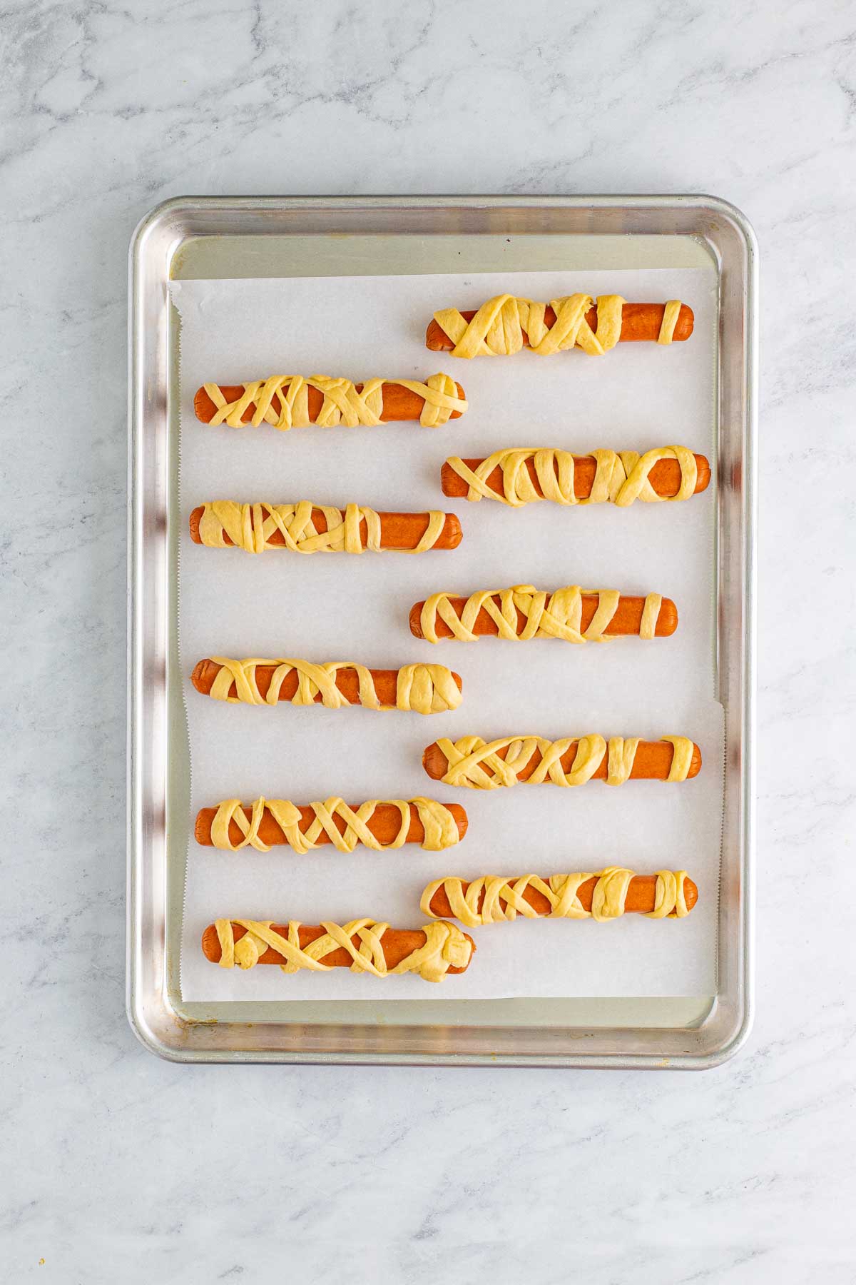 baking sheet with unbaked Halloween mummy dogs