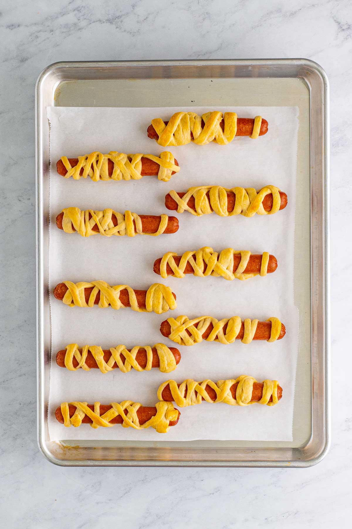 unbaked mummy hot dogs on a baking sheet