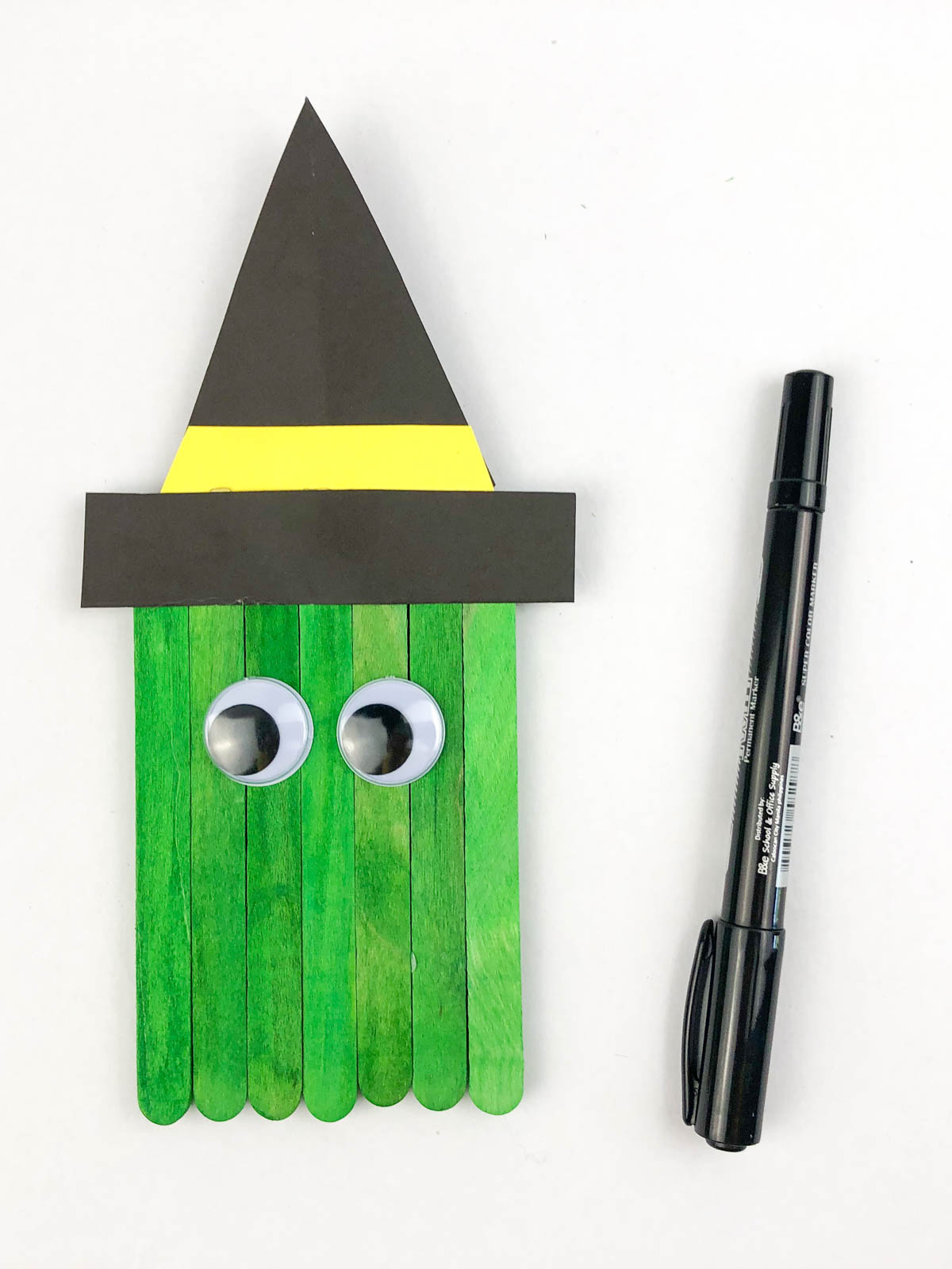 Green craft sticks with a witch hat and eyes