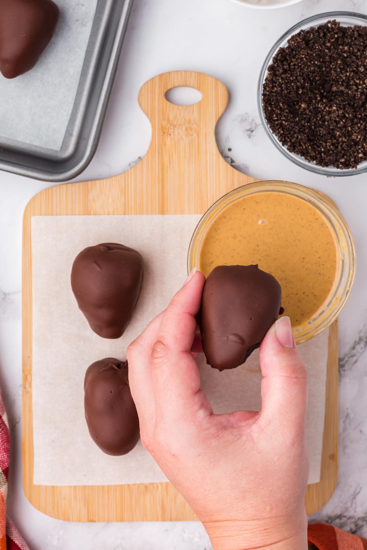 dipping a chocolate covered acorn in peanut butter 