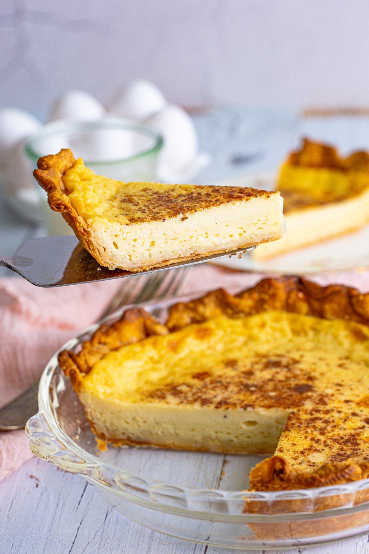 spatula with a slice of custard pie above a whole custard pie