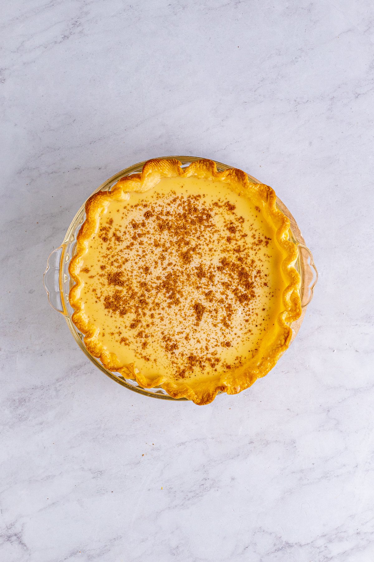 unbaked custard pie with nutmeg on top