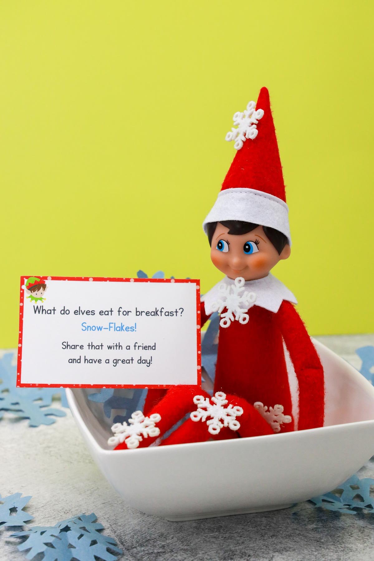 elf on the shelf sitting in a bowl of snowflakes