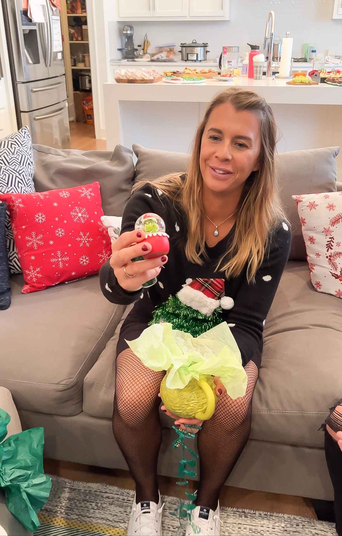 girl holding a Grinch mug and a Grinch snowglobe