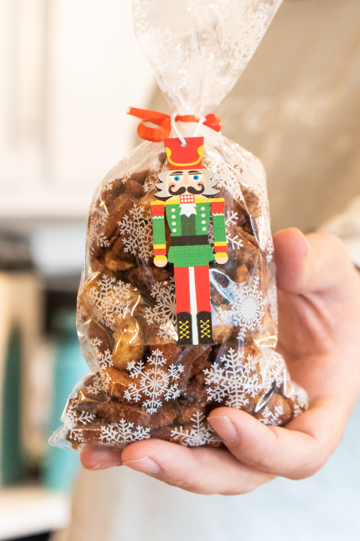 Hand holding a bag of candied nuts with a nutcracker ornament