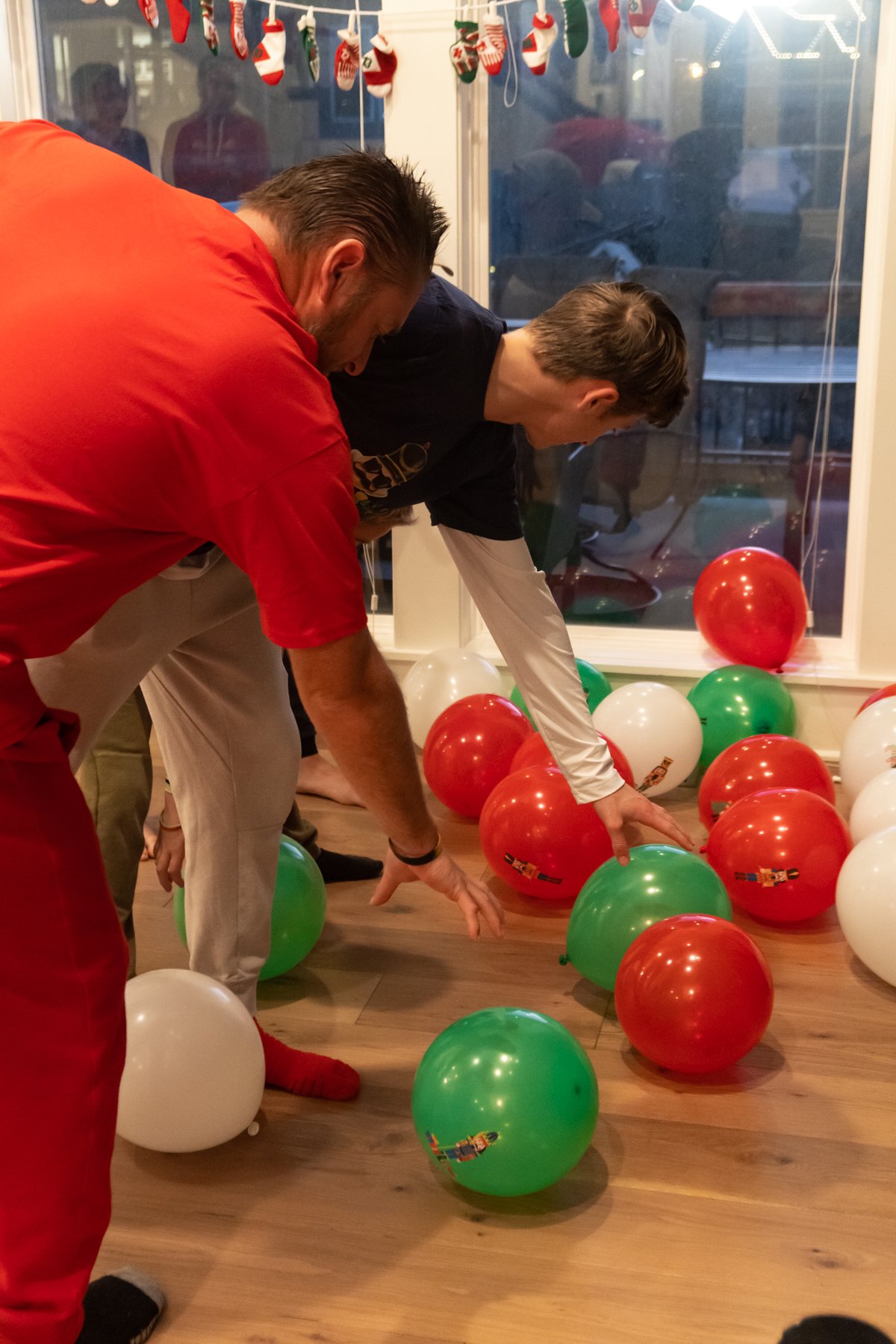 a son and father grabbing balloons off the ground