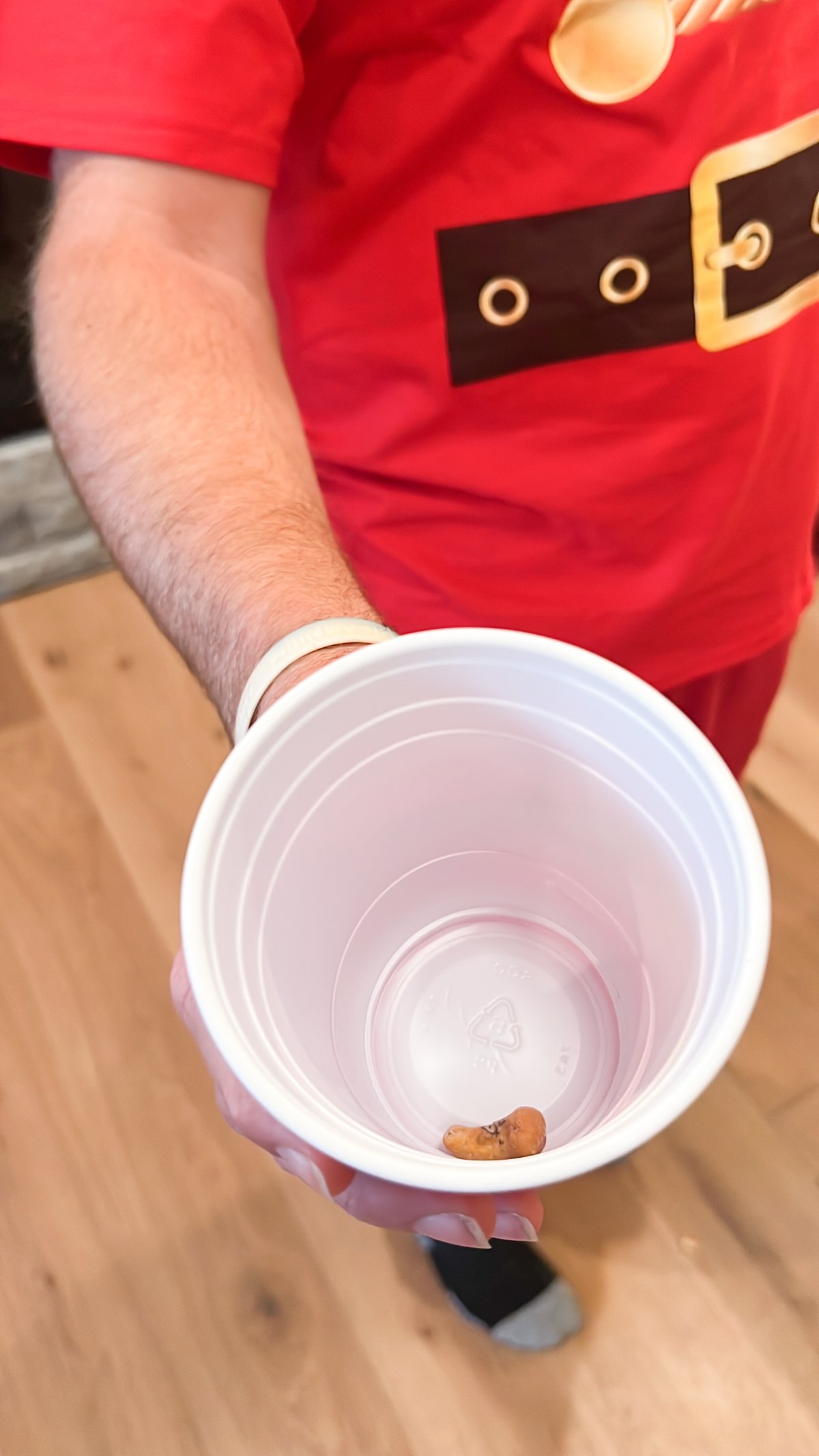 man holding a cup with a cashew in it