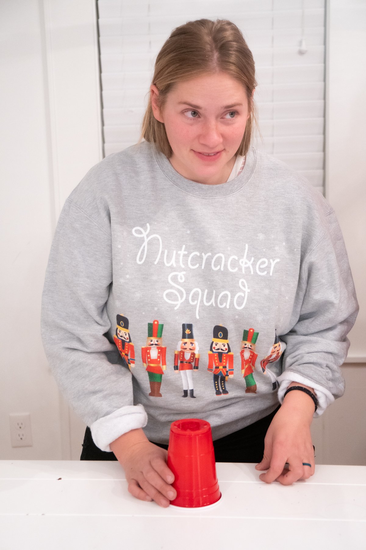 girl with a red cup in a nutcracker sweatshirt