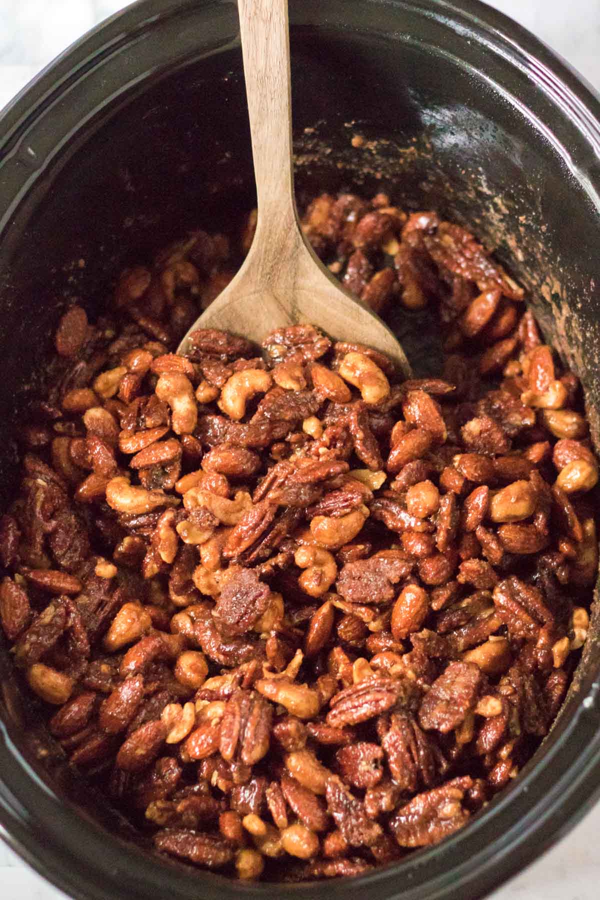 slow cooker with a spoon in some candied nuts